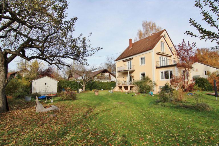 Einfamilienhaus mit Garten in Herrsching am Ammersee, umgeben von Bäumen und Laub.
