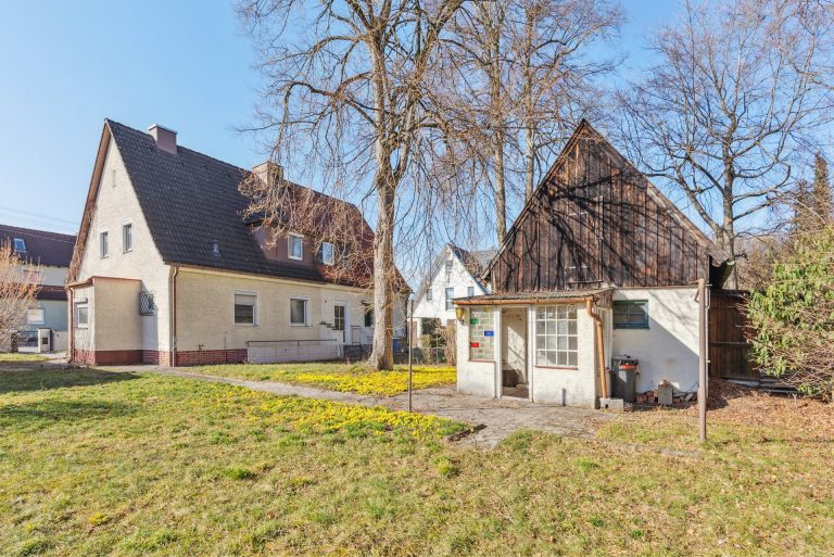 Zwei Wohnhäuser in einer ruhigen Umgebung mit einem Garten und Bäumen im Vordergrund.