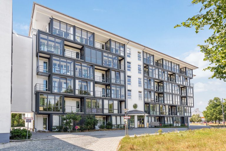 Moderne Wohnanlage mit mehreren Balkonen und großen Fenstern in einem urbanen Umfeld.