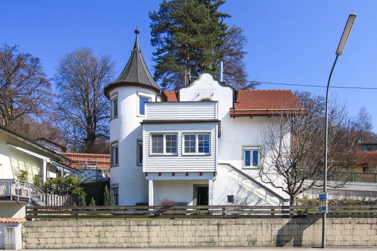 Weißes Haus in Sauerlach mit einem Turm und Holzverkleidung an der Fassade.