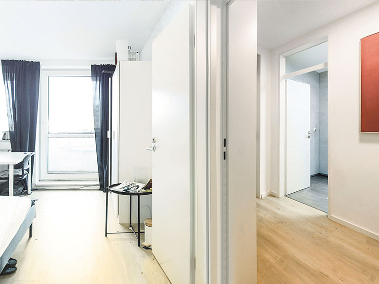 Innenansicht einer modernen Wohnung mit weißen Türen und Fenster zur natürlichen Beleuchtung.