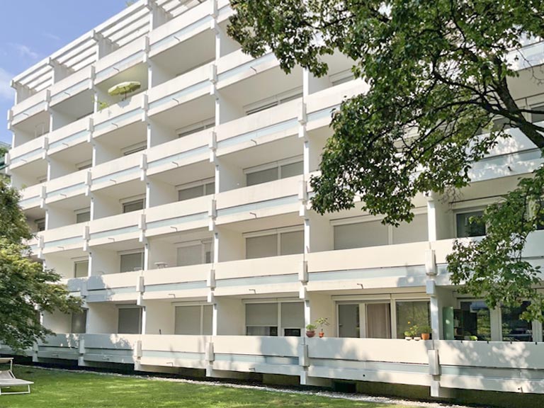 Helles mehrgeschossiges Wohngebäude mit weitläufigen Balkonen und grüner Außenanlage in München zum Immobilienkauf